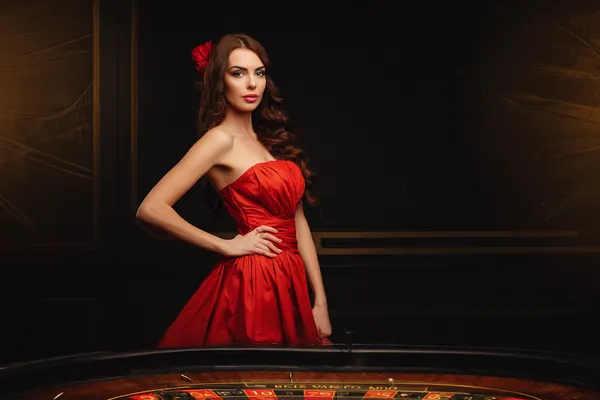 A young woman relaxing with her phone while dynamic casino elements float around her, illustrating the smooth mobile experience offered by the CROWNBD app.