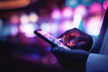 A woman smiling by bright slot machines showing lucky symbols, showcasing the exciting slot offerings at CROWNBD.